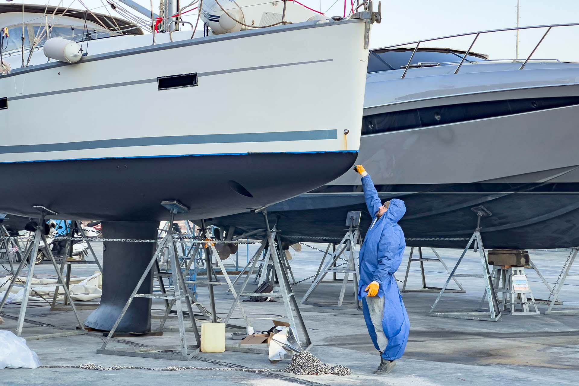 En man underhåller botten på en segelbåt på land.