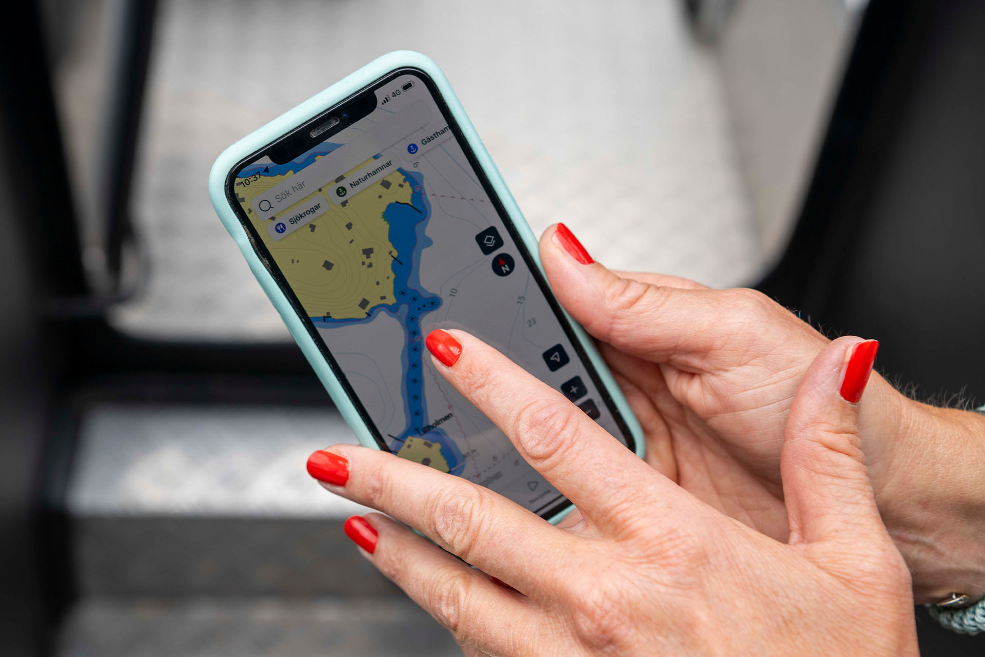 En hand håller i en telefon med en navigationsapp på skärmen.