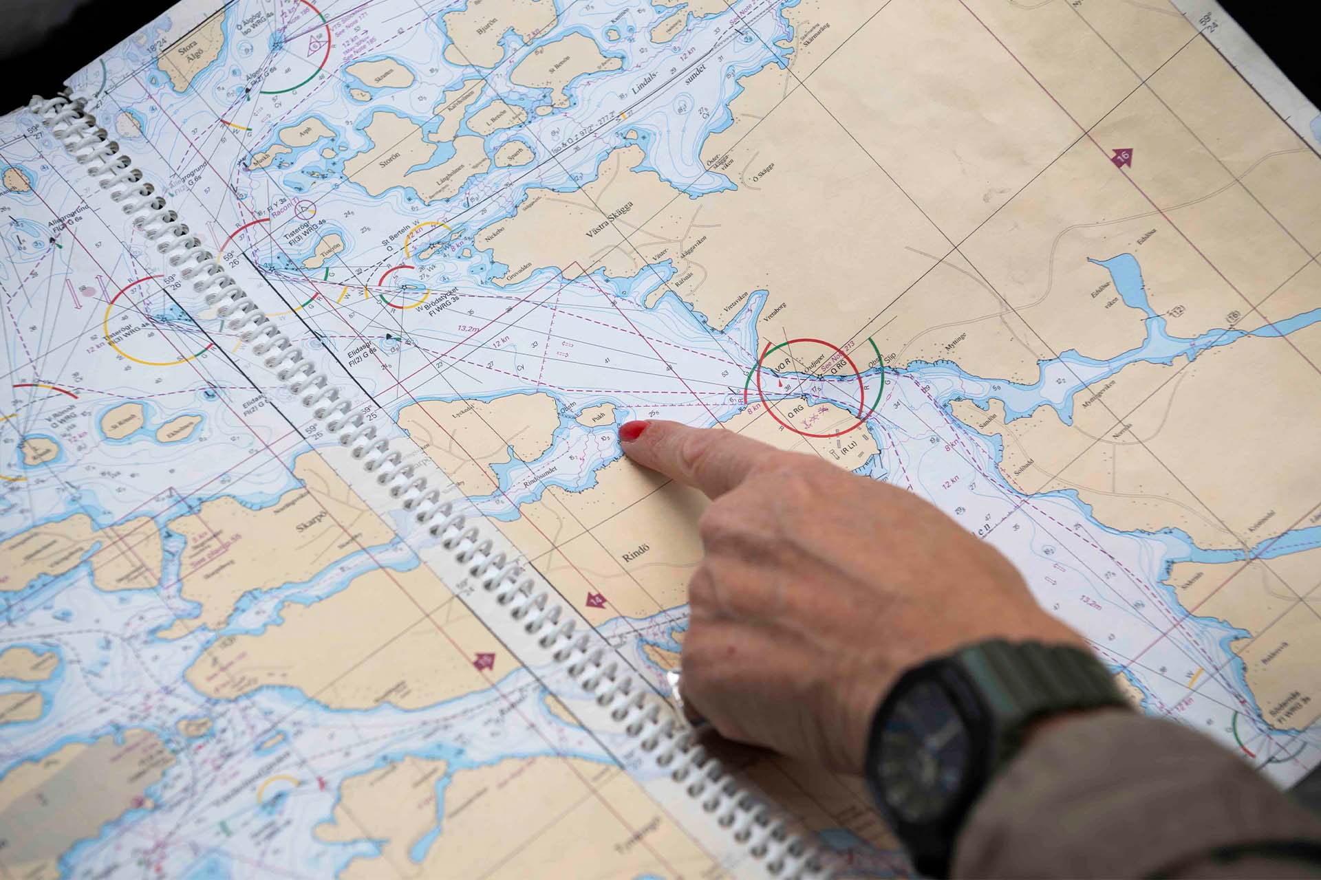 Bild på ett sjökort med skärgård. Ett finger pekar på en ö.
